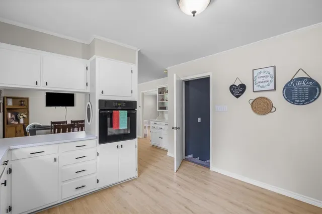 a kitchen with stainless steel appliances white cabinets and wooden floor