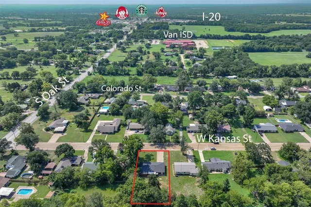 an aerial view of residential houses with outdoor space and trees