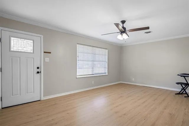 a view of empty room with wooden floor and fan