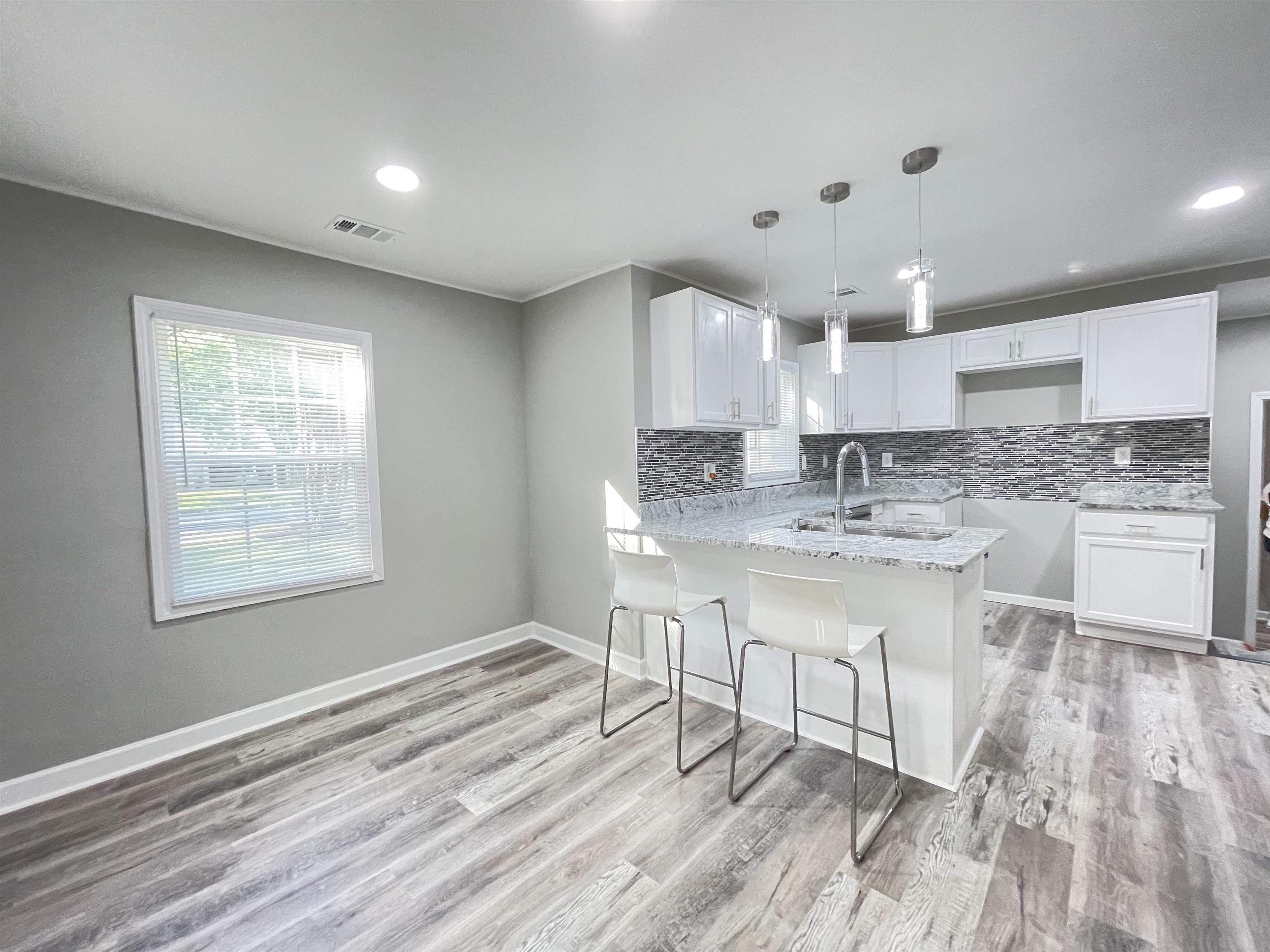 4409 Boyce Road Memphis, TN 38117 - Photo 4 of 25 a kitchen with kitchen island granite countertop a sink cabinets and wooden floor
