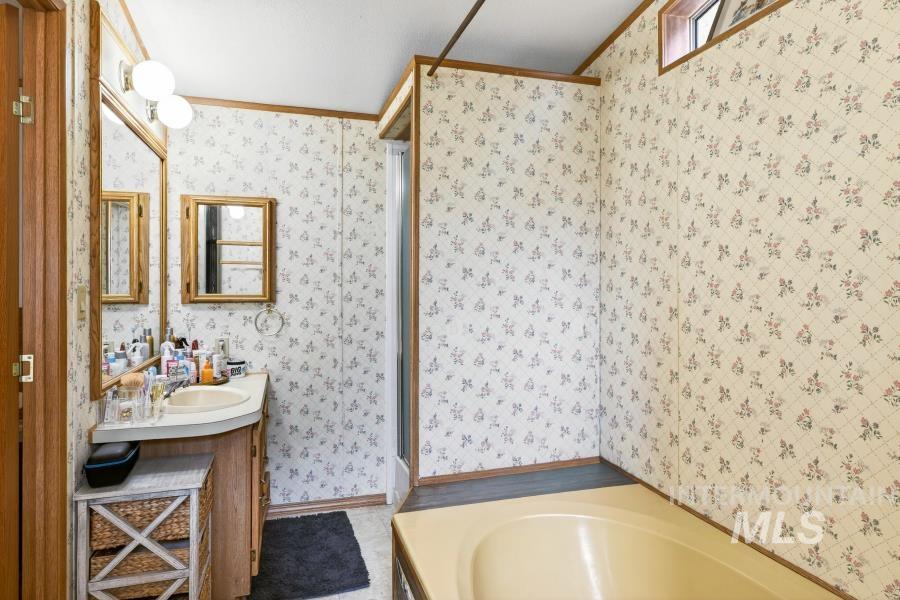 609 North Almon Street, Unit 3024 Moscow, ID 83843 - Photo 13 of 17 Bathroom featuring a garden tub, vanity, a stall shower, wallpapered walls, and ornamental molding