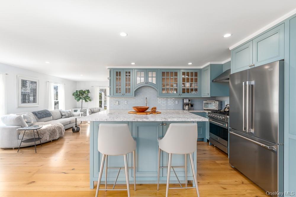 19000 Main Road Mattituck, NY 11952 - Photo 6 of 32 Kitchen with premium appliances, wall chimney exhaust hood, a kitchen breakfast bar, decorative backsplash, and recessed lighting