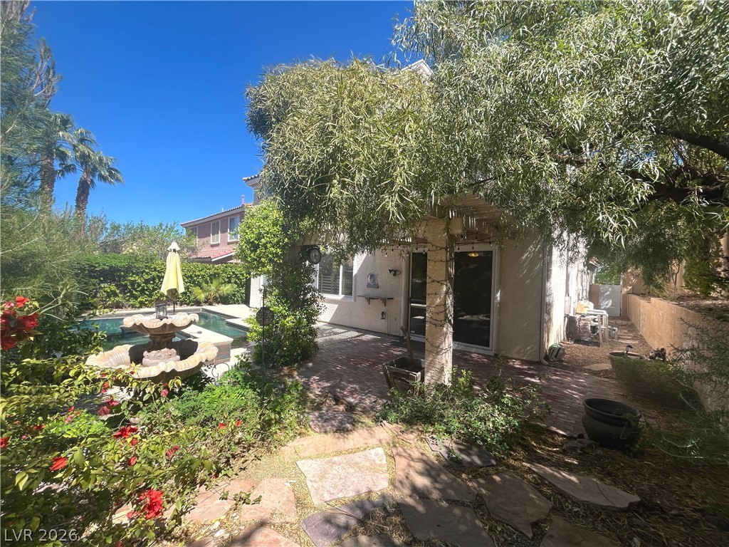 1809 Snow Spring Lane Las Vegas, NV 89134 - Photo 57 of 75 Step outside to the covered patio w/lush landscaping & indulge in the inviting pool or unwind in the soothing spa—a fantastic setting for relaxation and outdoor enjoyment.