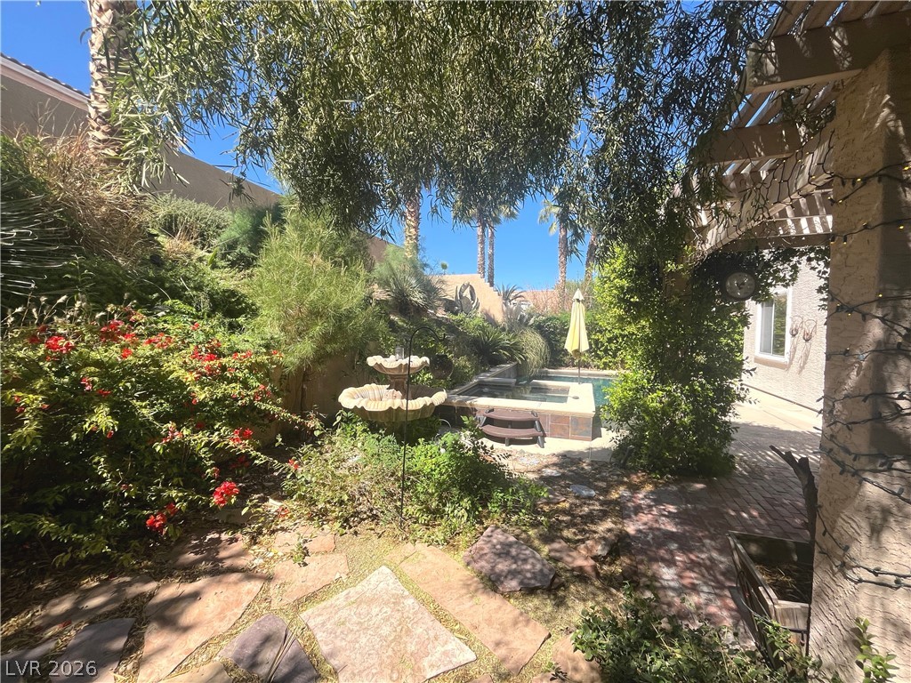 1809 Snow Spring Lane Las Vegas, NV 89134 - Photo 58 of 75 Step outside to the covered patio w/lush landscaping & indulge in the inviting pool or unwind in the soothing spa—a fantastic setting for relaxation and outdoor enjoyment.