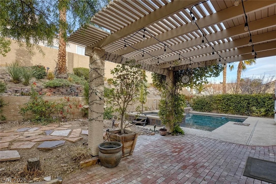 1809 Snow Spring Lane Las Vegas, NV 89134 - Photo 61 of 75 Step outside to the covered patio w/lush landscaping & indulge in the inviting pool or unwind in the soothing spa—a fantastic setting for relaxation and outdoor enjoyment.