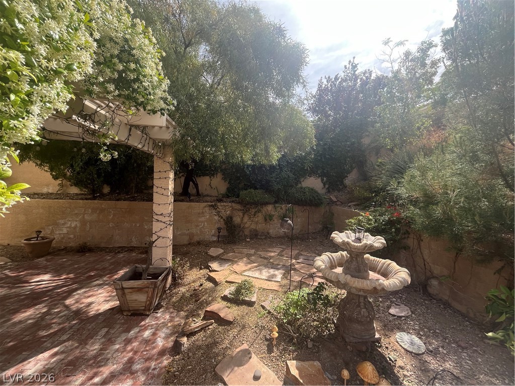 1809 Snow Spring Lane Las Vegas, NV 89134 - Photo 61 of 79 Step outside to the covered patio w/lush landscaping & indulge in the inviting pool or unwind in the soothing spa—a fantastic setting for relaxation and outdoor enjoyment.