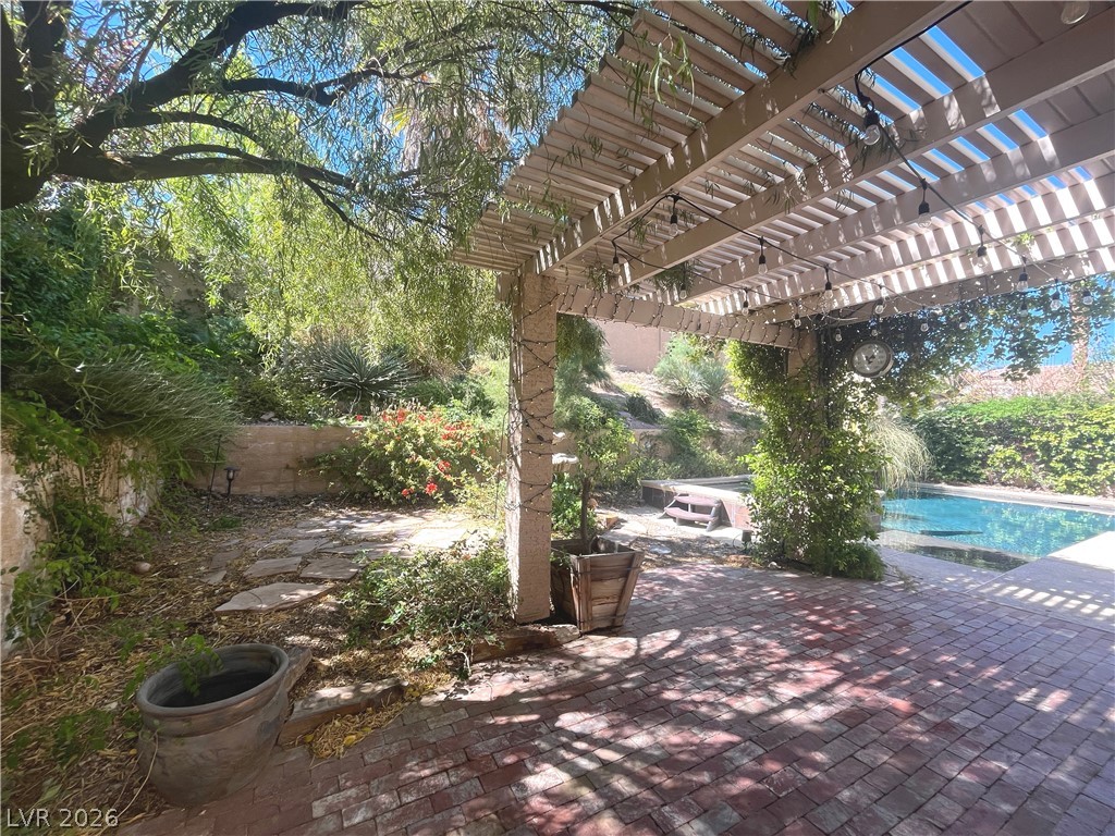 1809 Snow Spring Lane Las Vegas, NV 89134 - Photo 62 of 75 Step outside to the covered patio w/lush landscaping & indulge in the inviting pool or unwind in the soothing spa—a fantastic setting for relaxation and outdoor enjoyment.