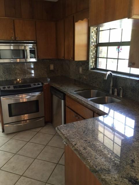 2055 Christensen Drive Navarre, FL 32566 - Photo 13 of 25 a kitchen with stainless steel appliances granite countertop a stove a sink and a microwave