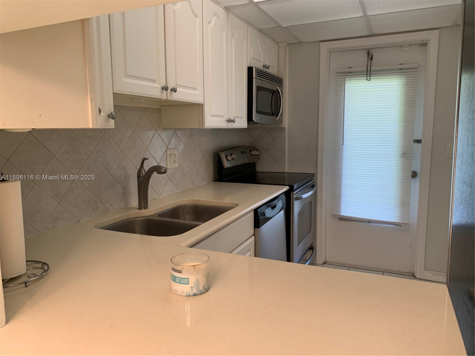 400 Northeast 20th Street, Unit A108 Boca Raton, FL 33431 - Photo 8 of 35 a kitchen with stainless steel appliances granite countertop a sink and a refrigerator