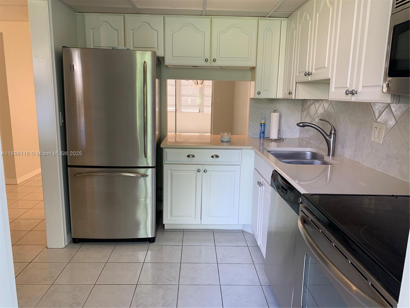 400 Northeast 20th Street, Unit A108 Boca Raton, FL 33431 - Photo 10 of 35 a kitchen with a refrigerator sink and cabinets