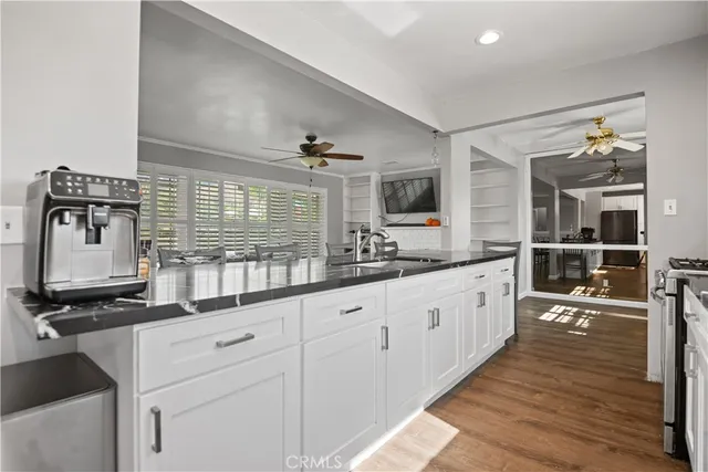 a large white kitchen with granite countertop a sink and dishwasher a stove with wooden floor