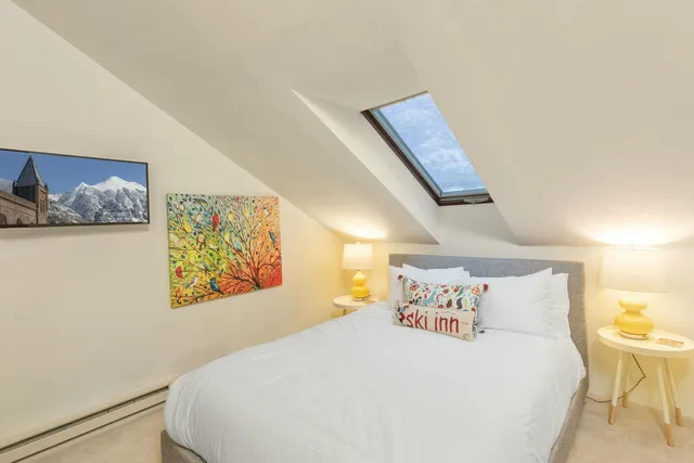 a bedroom with a bed and painting on the wall