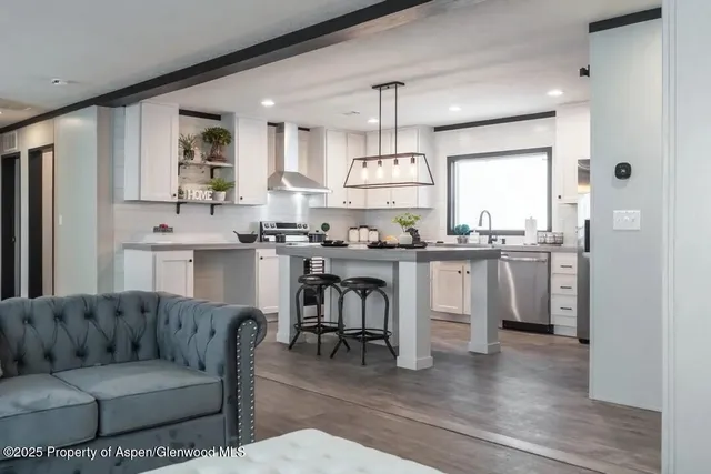 a living room with stainless steel appliances kitchen island granite countertop furniture and wooden floor