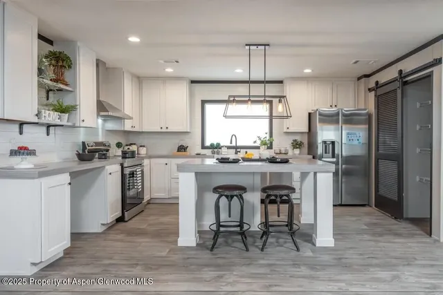 a kitchen with white cabinets stainless steel appliances and dining table