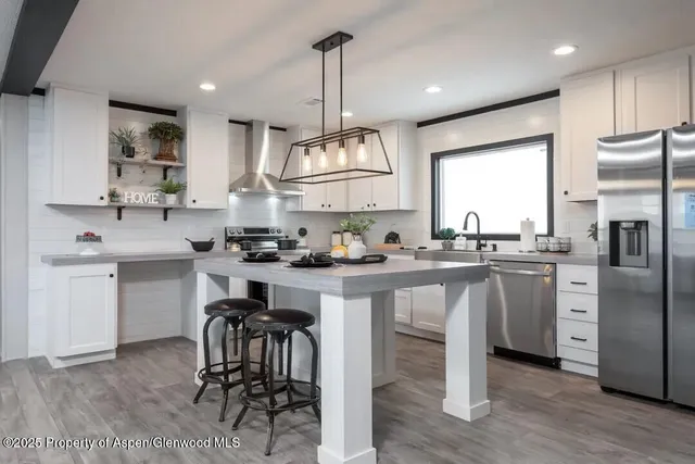 a kitchen with kitchen island granite countertop a sink a counter space appliances and cabinets