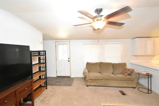 a living room with couches and kitchen view with wooden floor
