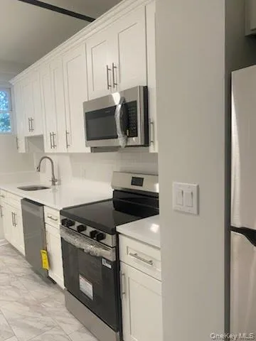 a kitchen with stainless steel appliances white cabinets and a stove top oven