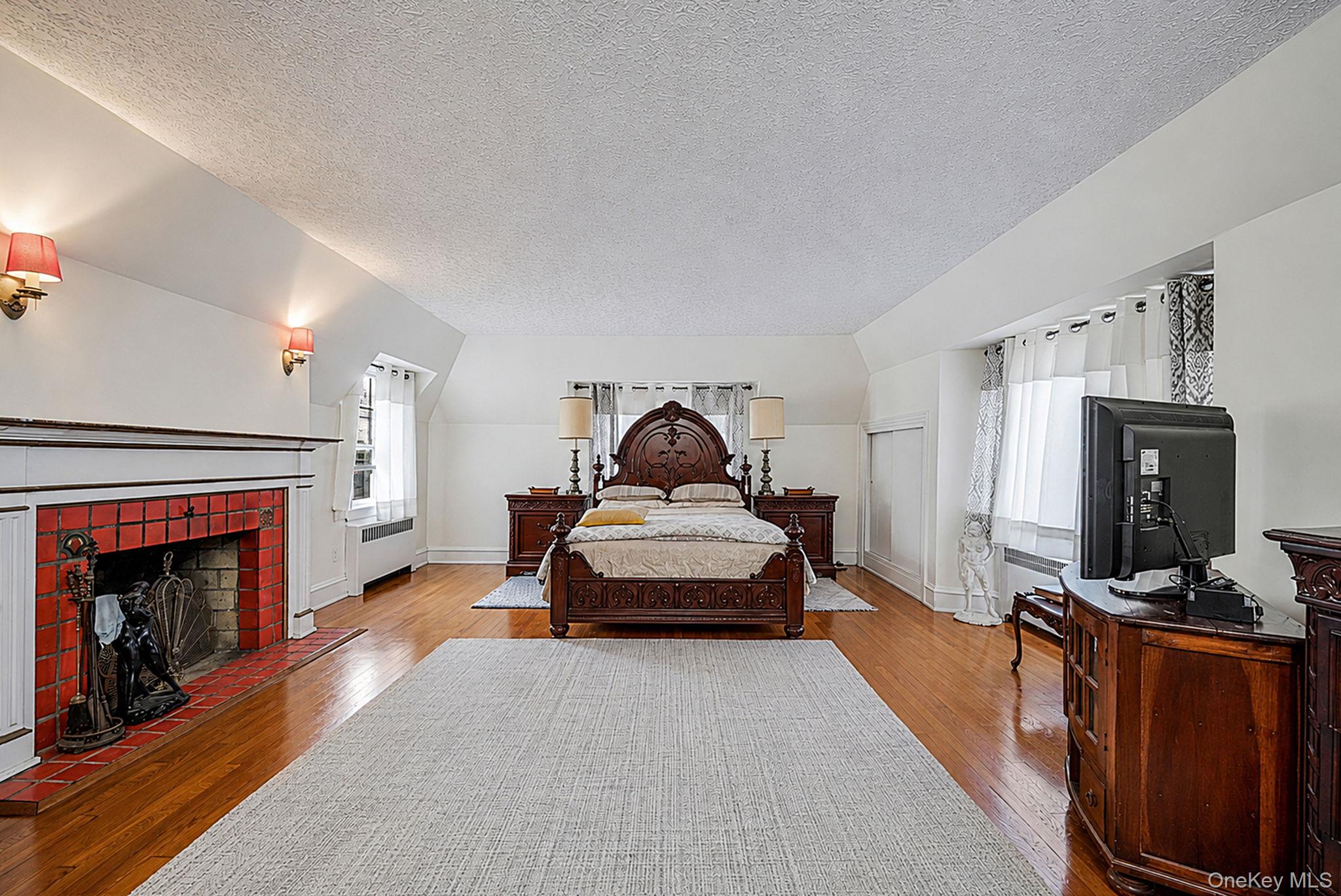 18240 Avon Road Queens, NY 11432 - Photo 17 of 30 Room featuring polished wood flooring, a decorative fireplace with red tile surround, and multiple windows