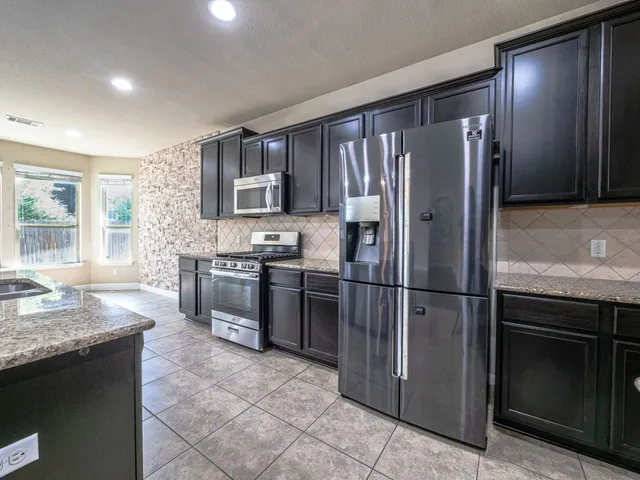 a kitchen with stainless steel appliances granite countertop a refrigerator stove and sink