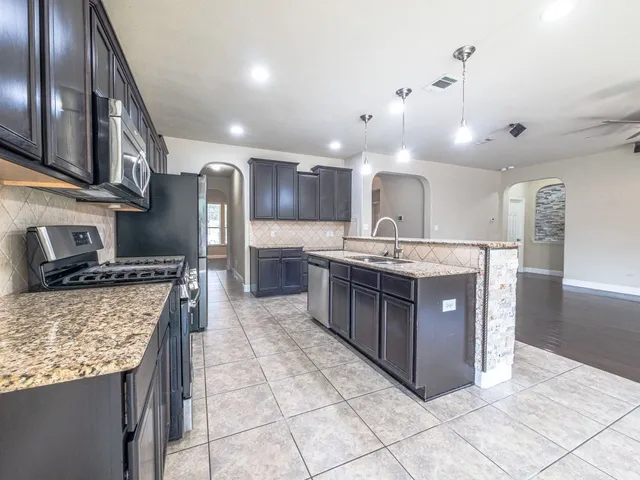 a kitchen with stainless steel appliances granite countertop a stove a sink a oven and a refrigerator