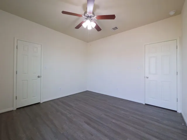 a view of a room with wooden floor and a ceiling fan