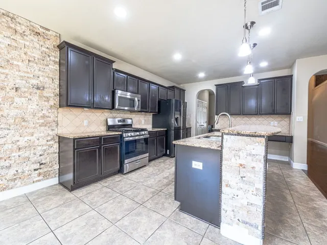 a kitchen with stainless steel appliances granite countertop a stove refrigerator sink and cabinets