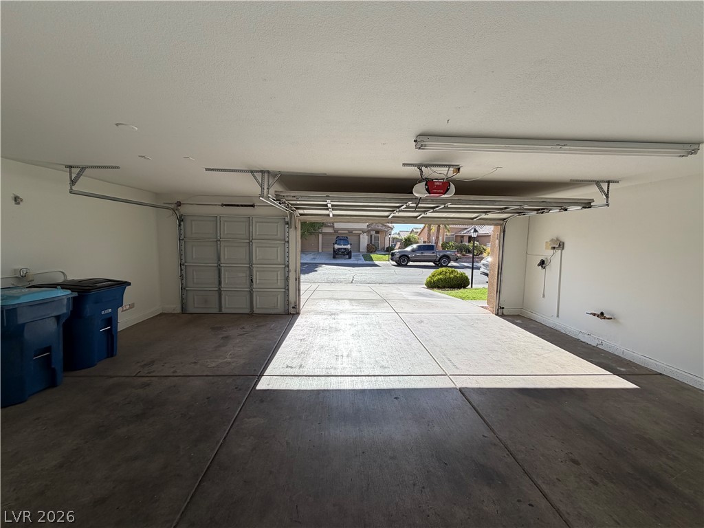 7613 Roop Street Las Vegas, NV 89131 - Photo 23 of 25 A spacious garage features durable concrete flooring and wide automatic doors opening to the driveway.
