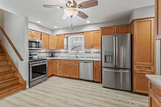 a kitchen with stainless steel appliances granite countertop a refrigerator a sink dishwasher a stove and white cabinets with wooden floor