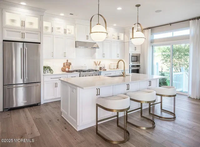 a kitchen with stainless steel appliances a dining table chairs stove refrigerator and cabinets