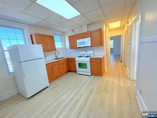 a kitchen with stainless steel appliances granite countertop wooden floors a stove and a refrigerator