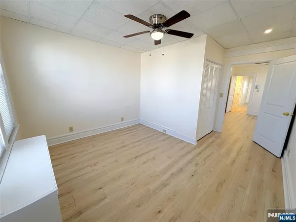 an empty room with wooden floor and a ceiling fan
