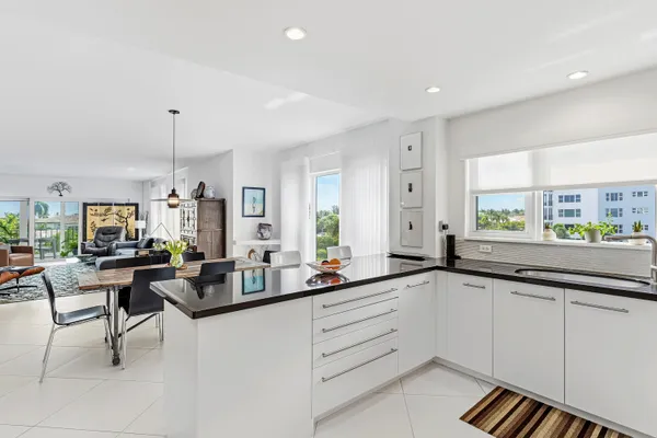 a large kitchen with granite countertop a sink and white cabinets with wooden floor