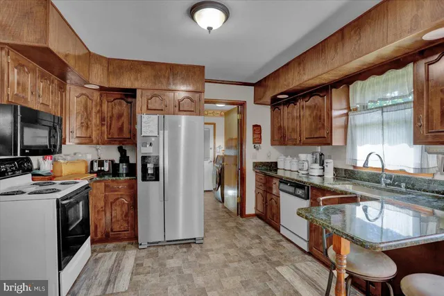 a kitchen with granite countertop a table chairs stove microwave and cabinets