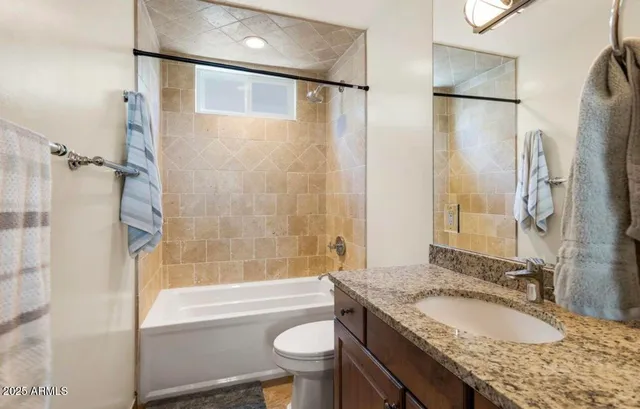 a bathroom with a granite countertop bathtub shower sink vanity and toilet
