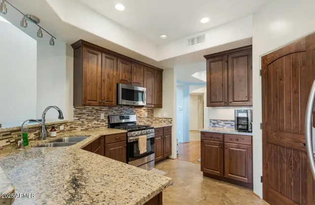 a kitchen with stainless steel appliances granite countertop a stove top oven a sink dishwasher a refrigerator and a microwave