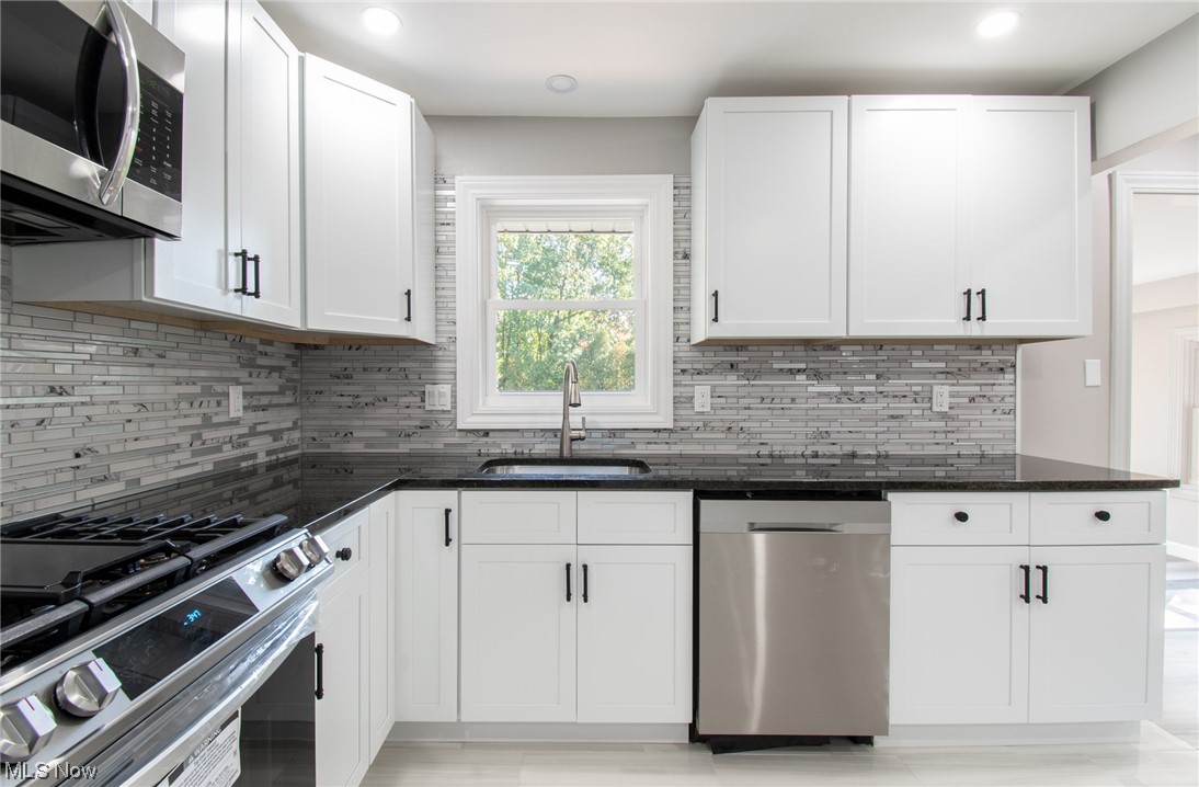 1097 South Meridian Road Youngstown, OH 44511 - Photo 4 of 29 Kitchen featuring white cabinets, dark stone countertops, stainless steel appliances, and tasteful backsplash