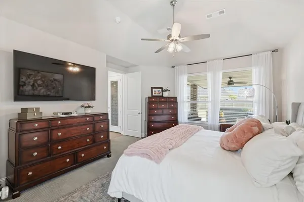 a bedroom with a bed a flat screen tv and a dresser