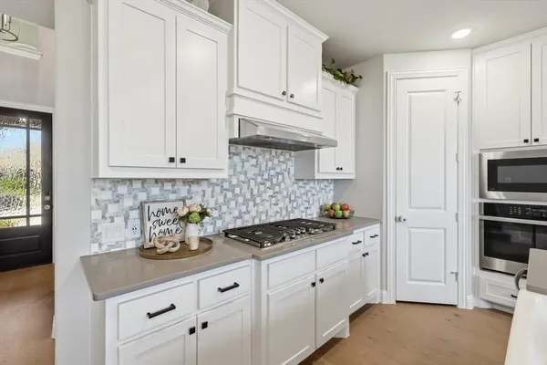 a kitchen with white cabinets and appliances