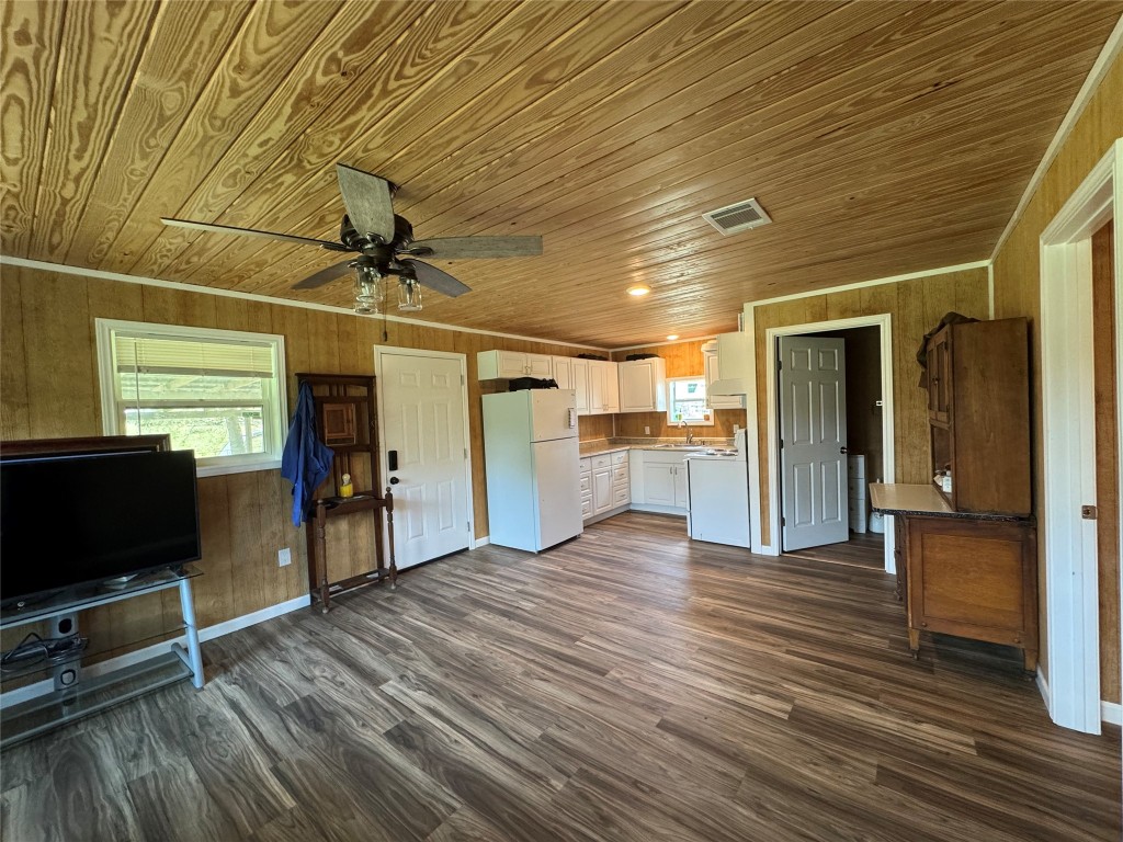 8060 County Road 210 Bertram, TX 78605 - Photo 31 of 40 Unfurnished living room featuring dark wood-style flooring, wood walls, wood ceiling, ornamental molding, and ceiling fan
