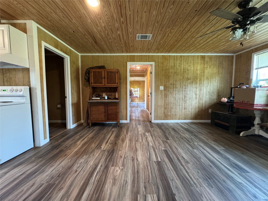 8060 County Road 210 Bertram, TX 78605 - Photo 34 of 40 Living area featuring wooden walls, dark wood-style floors, wood ceiling, a ceiling fan, and ornamental molding