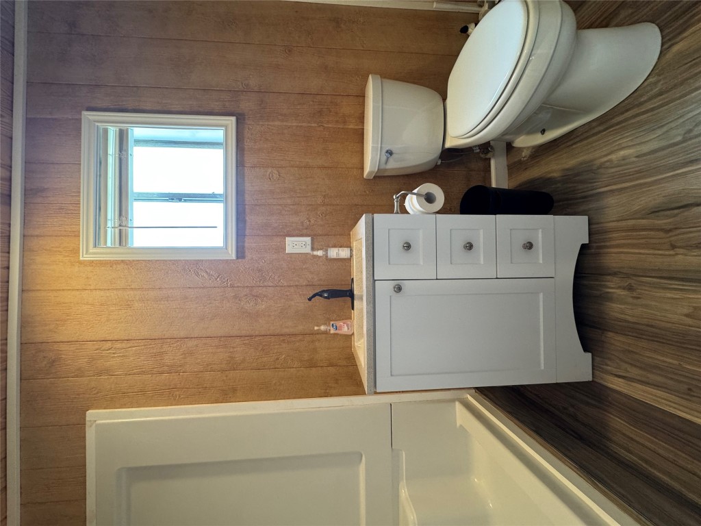 8060 County Road 210 Bertram, TX 78605 - Photo 37 of 40 Bathroom with dark wood finished floors, vanity, and wood walls