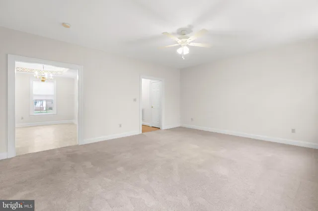 a view of an empty room with a chandelier fan