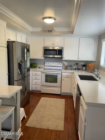 a kitchen with white cabinets appliances a sink and a large window