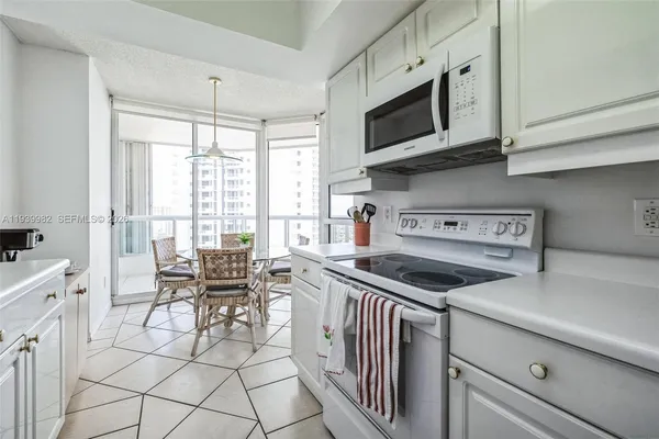 a kitchen with stainless steel appliances granite countertop a stove top oven a sink a dining table and chairs with white cabinets