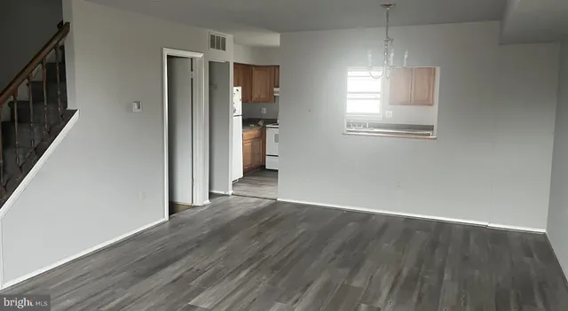 an empty room with wooden floor a ceiling fan and windows