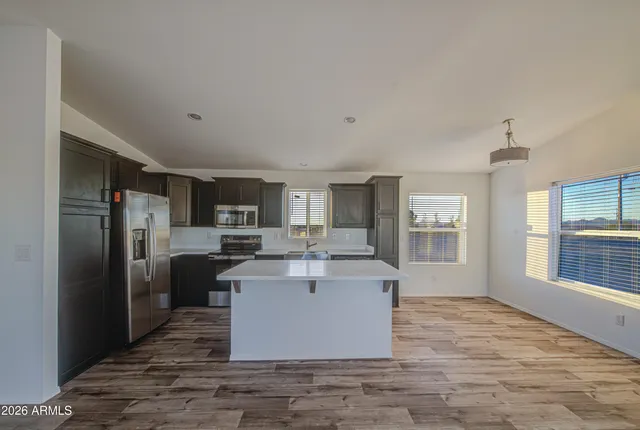 a living room with stainless steel appliances kitchen island granite countertop a refrigerator a sink a stove and a counter space
