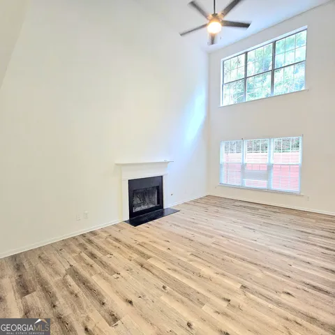 an empty room with wooden floor fireplace and windows