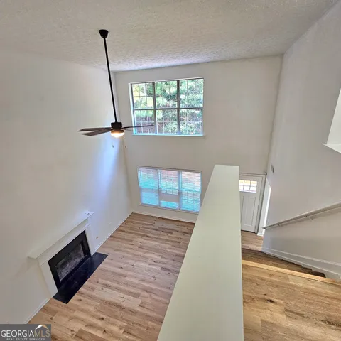 an empty room with wooden floor fan and windows
