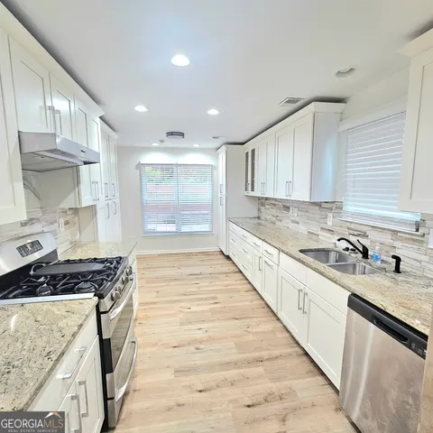 a large kitchen with kitchen island granite countertop white cabinets and stainless steel appliances