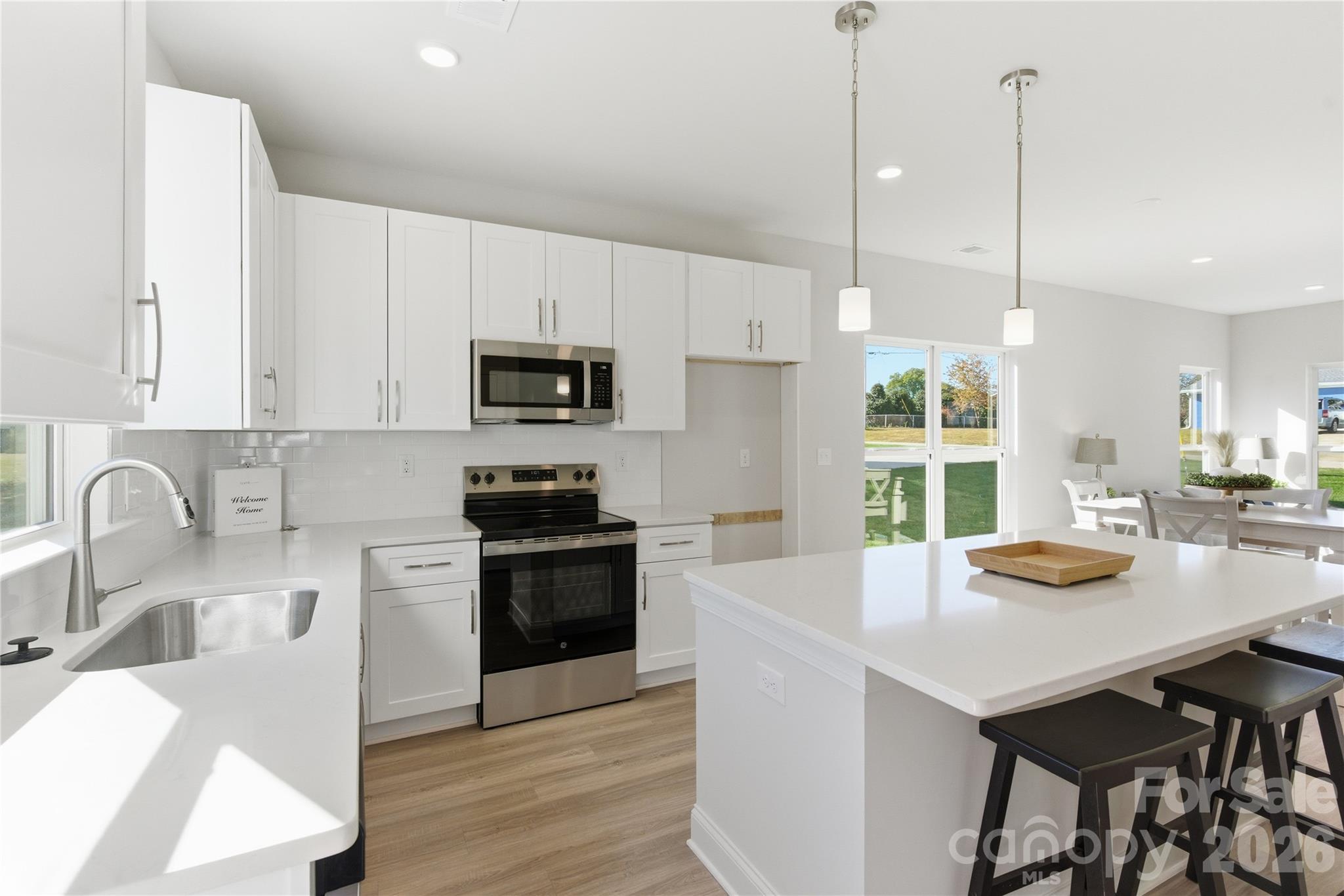 222 1st Street South Fort Mill, SC 29708 - Photo 4 of 23 a kitchen with a sink a stove and chairs with wooden floor